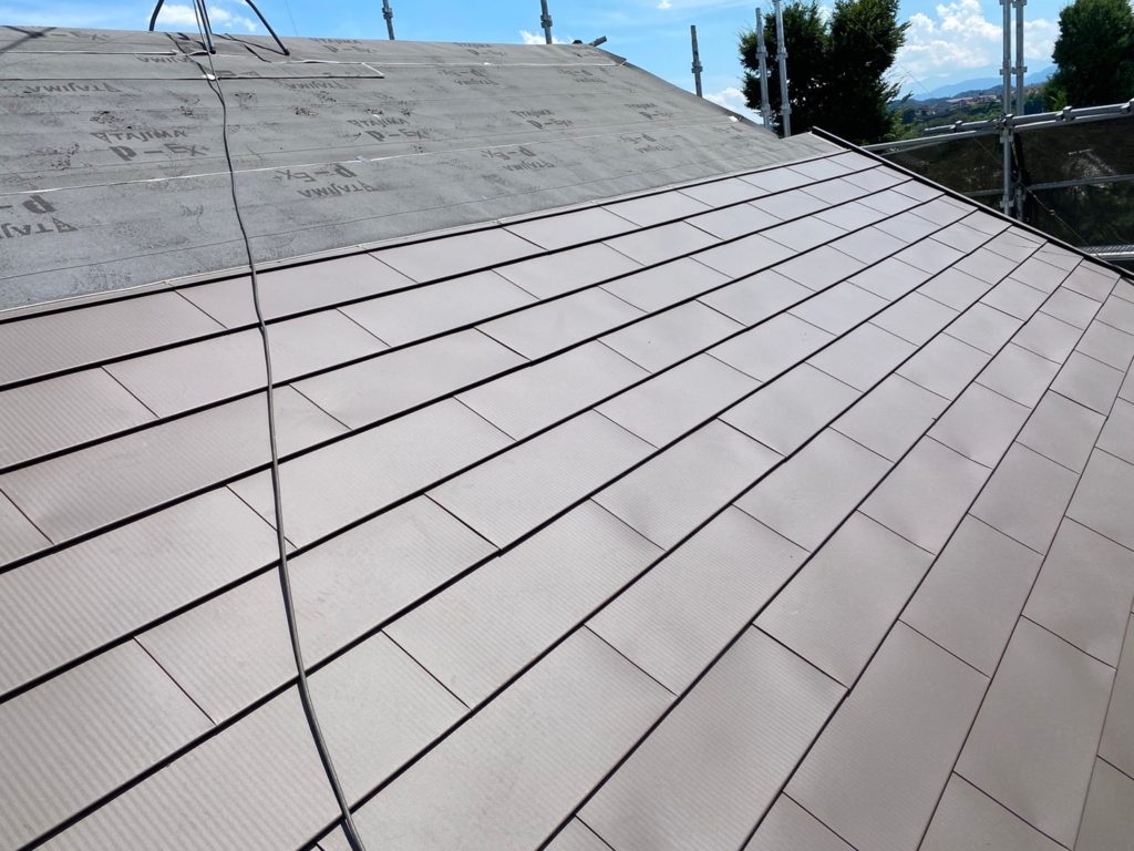 アスファルトルーフィングの上にガルバリウム鋼板の屋根を張り付けていきます。<br />
本来、棟板金の下地材は貫板(材木)であるが、弊社の					<br />
ほうは材木を使用しない、樹脂製品の貫板を使用。					<br />
					<br />
